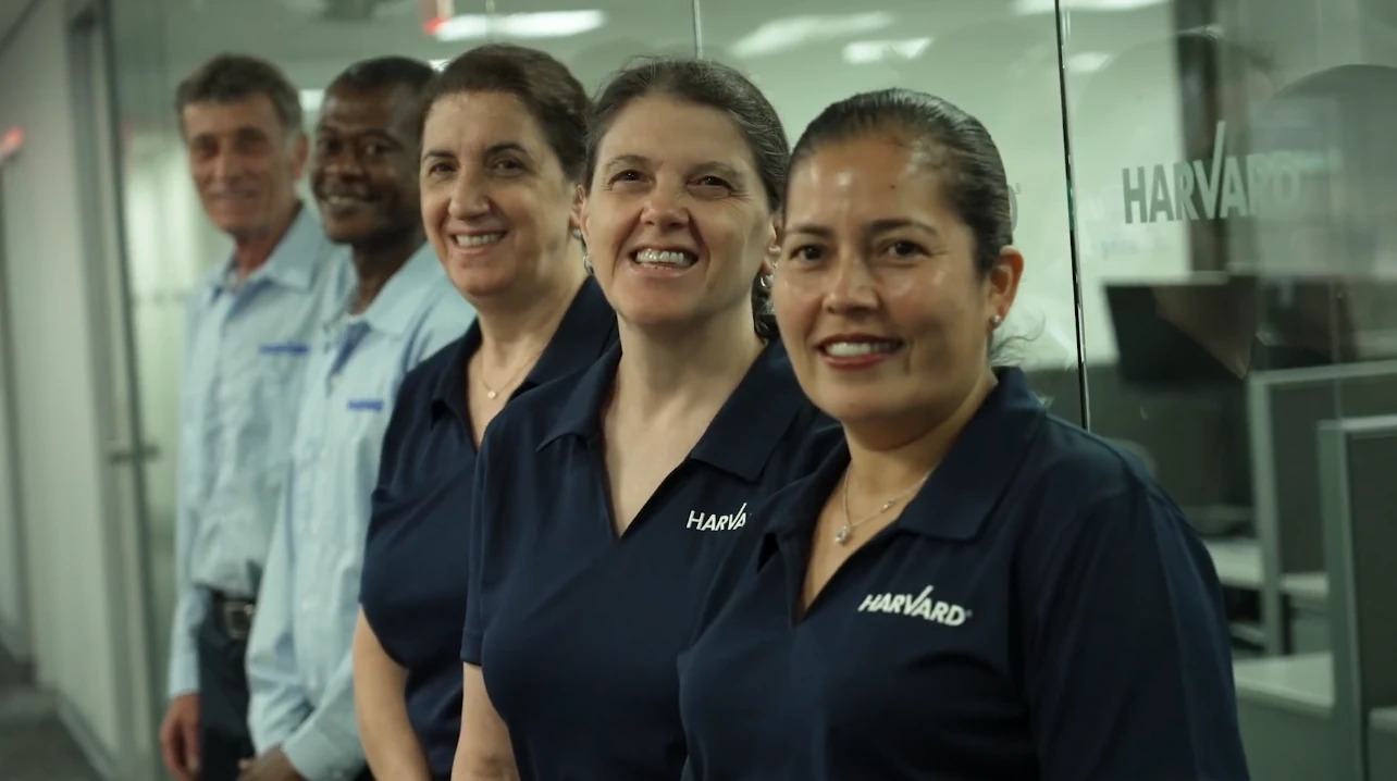 Five Harvard staff members stand in a row smiling in an office.