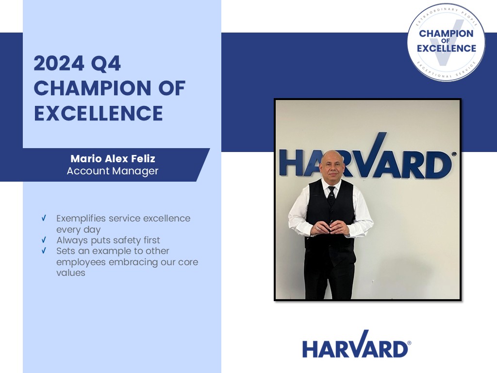 Mario Alex Feliz stands in front of a Harvard sign, recognized as 2024 Q4 Champion of Excellence.
