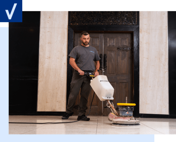 Construction Cleaning – check mark left Man operating a floor cleaning machine on a polished marble floor in front of a closed door.