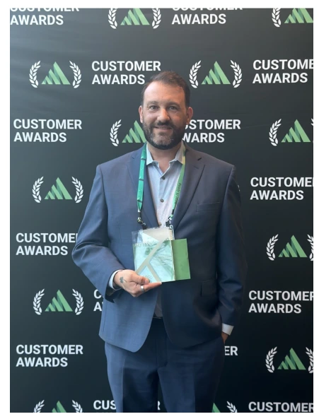 Man in a suit holding an award in front of a